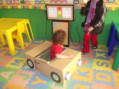 a young child playing in a cardboard box at a children's play area with toys