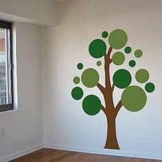 a room with a tree painted on the wall next to a window and hard wood floor