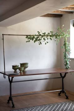 a table with two vases on it in front of a window and a potted plant