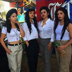 four women standing next to each other in front of a building with graffiti on it