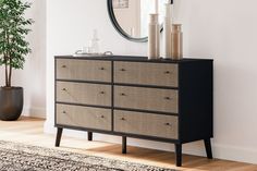 a black and brown dresser with two vases on it next to a round mirror