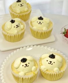 four cupcakes with white frosting and black ears on them sitting on a plate