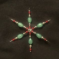 a green and red beaded snowflake on a black background