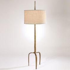 a floor lamp with a beige shade on it's side and a white background