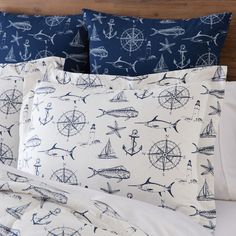 a bed with blue and white nautical themed sheets, pillows and pillow cases on it