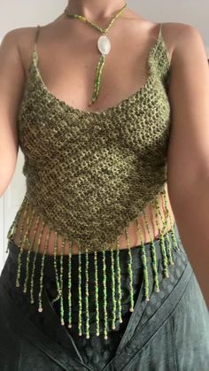 a woman wearing a green tank top with fringes on it's sides and a chain around her waist