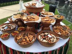 a table topped with lots of food on top of a lush green field