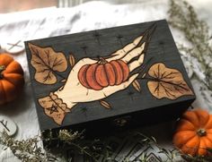 a wooden box sitting on top of a table with pumpkins and leaves around it