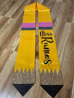 two yellow scarfs with pink, purple and black stripes that say miss grace on them