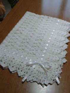 a white crocheted doily sitting on top of a wooden table next to a brown dog