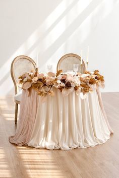 the table is set with two chairs and flowers on it, along with three candles