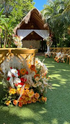 an outdoor wedding setup with chairs and flowers on the grass, surrounded by palm trees