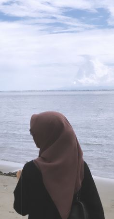 a woman sitting on top of a beach next to the ocean