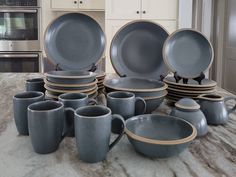 a table topped with lots of gray dishes next to a stove top oven and microwave