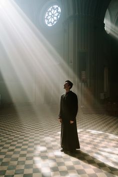 a man standing in the middle of a church with sunlight streaming through the window behind him