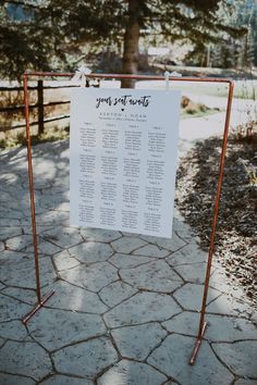 a sign that is on top of a metal stand with a tree in the background