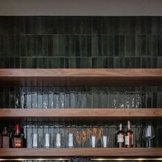 the shelves are filled with liquor bottles and glasses