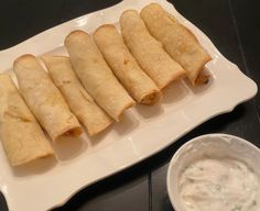 a white plate topped with lots of food next to a bowl of ranch dips