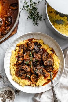 a plate with mashed potatoes and mushrooms on it next to two bowls of food