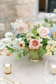 a vase filled with flowers on top of a table next to gold candlesticks