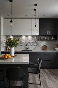 a kitchen with black and white cabinets, marble counter tops, and wooden flooring