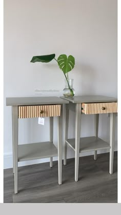 two wooden tables with drawers and a plant in a vase on the top one side