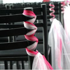 several chairs with pink and white ribbons on them