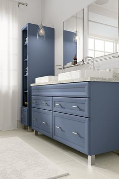 a bathroom with blue cabinets and marble counter tops, along with a white rug on the floor