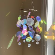 a wind chime hanging from the side of a window with sun shining through it