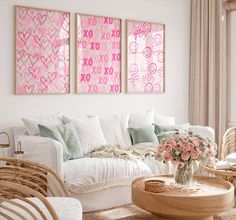 a living room with wicker furniture and pink paintings on the wall above it's couch