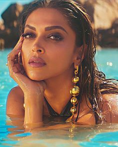 a woman in the water with her hand on her head and looking at the camera