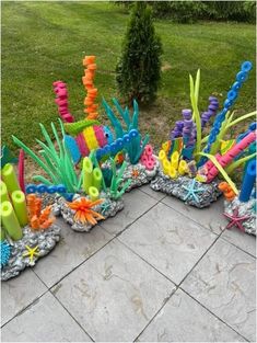 an assortment of colorful plastic sea life on display in a garden area with grass and flowers