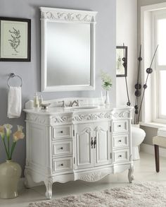 a bathroom with a white vanity, mirror and flowers in vases on the floor