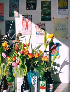 several bottles with flowers in them sitting on a table next to some posters and papers