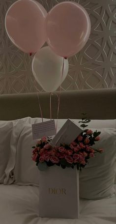 some balloons are floating in the air over a bed with flowers and a note on it