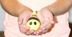 a child holding a yellow toy with a smiley face on it's head and hands