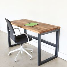 a desk with a laptop on it and a chair next to it in front of a wall