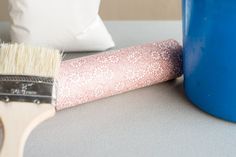 a brush sitting on top of a table next to a blue vase and pillow with white speckles