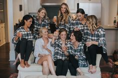 a group of women sitting on top of a couch holding wine glasses in their hands