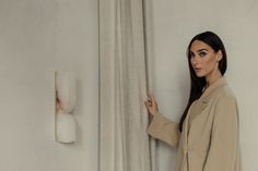 a woman standing in front of a curtain with her hand on the side of the curtain