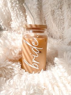 a mason jar with a straw in it sitting on a fluffy white blanket that says love