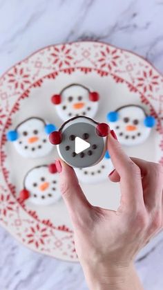 a woman holding a video game controller in front of a plate with snowmen on it