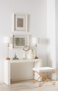 a white desk with two lamps and pictures on the wall