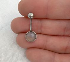 a person is holding a nose ring with a stone in the middle and a ball at the end