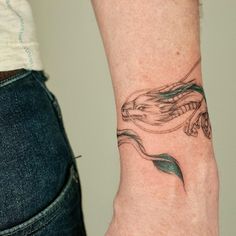 a woman's arm with a tattoo on it that has a bird and leaves on it