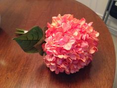 a pink flower sitting on top of a wooden table