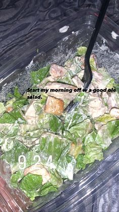 a salad with lettuce and chicken in a plastic container on a black table cloth