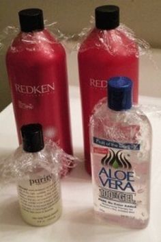 two bottles of aloe vera and redken on a white counter top with plastic wrap around them