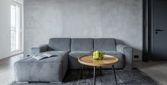 a gray couch sitting next to a wooden table on top of a rug in a living room