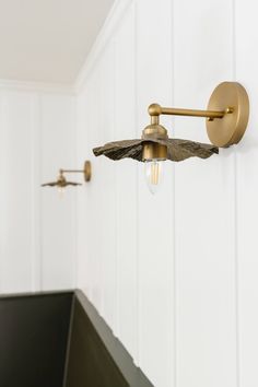 a bathroom light that is on the wall next to a sink in a room with white walls